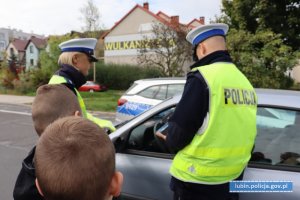 Policjanci wraz z dziećmi stoją przy samochodzie