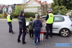 Policjanci i dzieci podczas akcji stoją przy kontrolowanym samochodzie