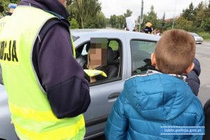 Policjantka z dziećmi przy zatrzymanym do kontroli samochodzie