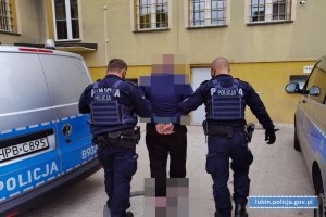 Policjanci prowadzą zatrzymanego mężczyznę