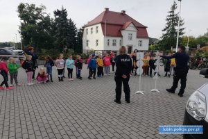 Policjanci na placu szkolnym rozmawiają z uczniami