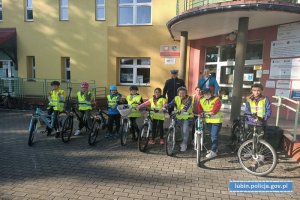 Zdjęcie policjanta z uczniami biorącymi udział w egzaminie na kartę rowerową