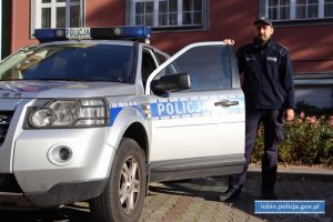 Policjant stoi przy radiowozie