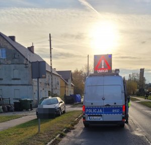 Radiowóz ruchu drogowego. Na dachu pojazdu ostrzeżenie o wypadku. W tle miejsce zdarzenia