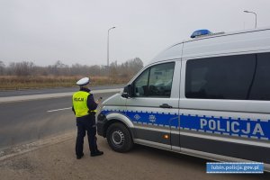 Policjantka stoi przy radiowozie. W ręce trzyma przyrząd do pomiaru trzeźwości