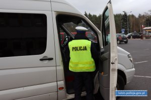 Policjant kontroluje przestrzeganie obowiązku zakrywania ust i nosa w środkach komunikacji pracowniczych