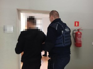 Policjant prowadzi zatrzymanego mężczyznę