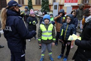 Policjantka rozdaje kamizelki dla grupy dzieci