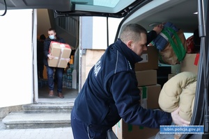 Policjanci pakują do samochodu kartony dla funkcjonariuszy z Ukrainy