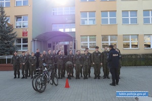 Policjant z klasą mundurową przed budynkiem szkoły