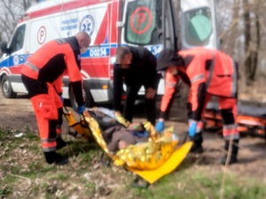 Zespół Pogotowia Ratunkowego i policjant przenoszą odnalezionego mężczyznę na nosze i do karetki