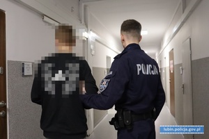 Policjant prowadzi zatrzymanego mężczyznę