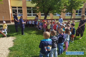 Policjant i policjantka na prelekcji. Funkcjonariusz pokazuje dzieciom znaki drogowe