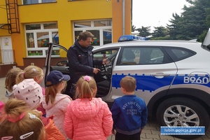 Policjant pokazuje dzieciom policyjny radiowóz i jego wyposażenie