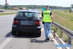 Policjant przy uszkodzonym pojeździe