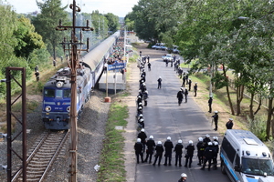 Policjanci stoją obok peronu stacji Lubin Stadion, obok z pociągu wysiadają kibice Śląska Wrocław