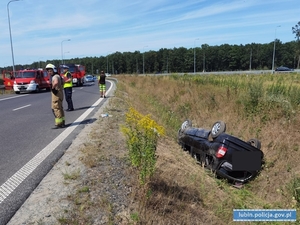 Miejsce wypadku drogowego, służby ratunkowe na miejscu. Auto w rowie