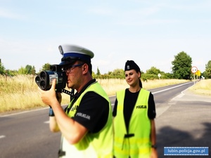 Policjant mierzy prędkość kierowców. Za nim stoi policjantka