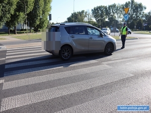 Miejsce wypadku drogowego - potrącenia pieszego. Policjant robi oględziny pojazdu