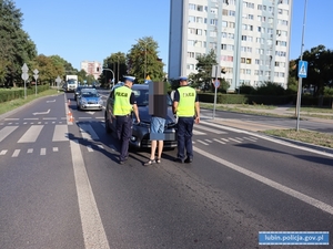 Miejsce wypadku drogowego - potrącenia pieszego. Policjanci robią oględziny pojazdu