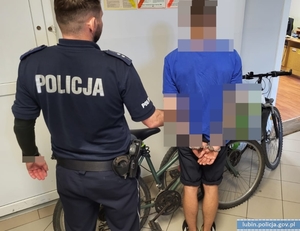 Policjant stoi z zatrzymanym mężczyzną przy odzyskanych rowerach