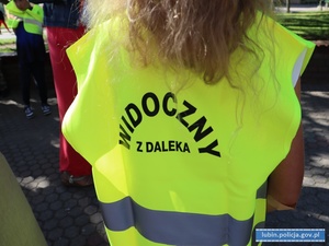 Dziecko w kamizelce odblaskowej z napisem widoczny z daleka