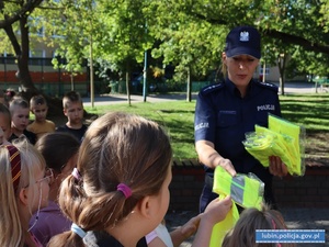 Policjantka rozdaje kamizelki odblaskowe