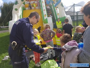 Policjant rozdaje dzieciom kamizelki odblaskowe