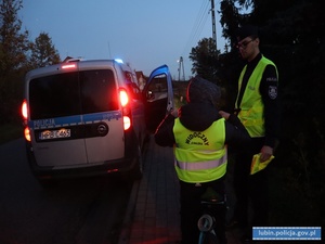 Policjant z  chłopcem, któremu przekazano kamizelkę odblaskową