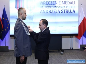 Minister wręcza medal dla sierż. szt. Piotra Tryby