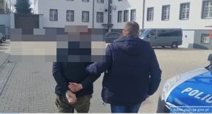 Policjant prowadzi zatrzymanego mężczyznę