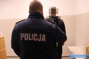 Policjant stoi z zatrzymanym mężczyzną