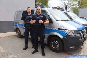 Policjanci stoją przy radiowozie