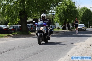 Policjant na motocyklu pilotuje uczestników biegu