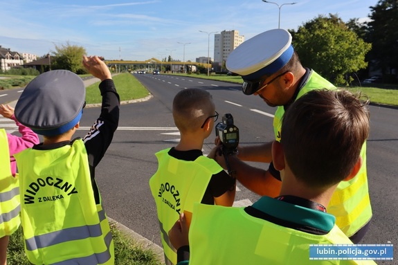 Policjant pokazuje dzieciom jak mierzy się prędkość kierującym