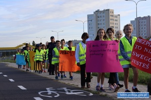Dzieci z transparentami i komisarzem lwem idą chodnikiem