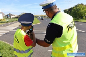 Policjant  z dziećmi mierzy prędkość kierowcom