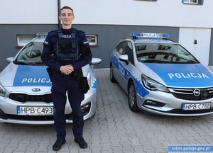 Policjant stoi przy dwóch radiowozach