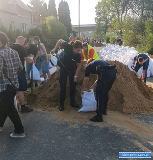 Policjantki pakują piasek do worków