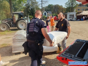 Policjanci pomagają przy pakowaniu worków z piaskiem