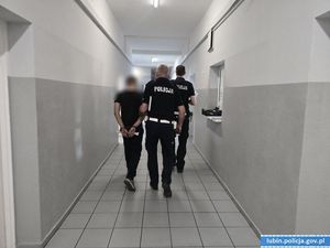 Policjanci prowadzą zatrzymanego kierowcę