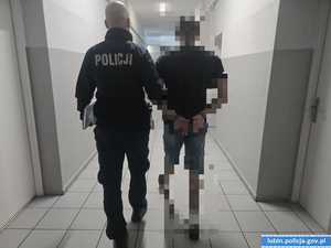 Policjant prowadzi zatrzymanego mężczyznę