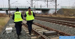 policjant i policjantka idący przy torach