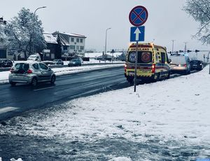 zaśnieżone pobocze , widać jak na prawym pasie drogi stoi karetka pogotowia i radiowóz policyjny