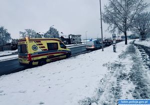 zaśnieżone pobocze , widać jak na prawym pasie drogi stoi karetka pogotowia i radiowóz policyjny