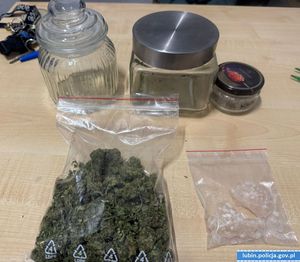 na zdjęciu od lewej strony stoi szklany pojemnik pusty obok szklany słoik pusty i ostatni mały słoik przed nimi lezy woreczek strunowy w środku susz roślinny koloru zielonego oraz drugi woreczek strunowy w środku białe kryształki