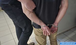 Mężczyzna stojący tyłem z kajdankami na rękach