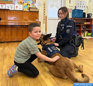 Chłopiec głaszcze policyjnego psa