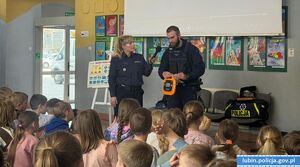Policjant prezentuje uczniom defibrylator AED