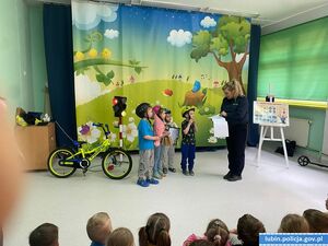 Kaski, rowery i przedszkolaki ćwiczące z policjantką zasady ruchu drogowego